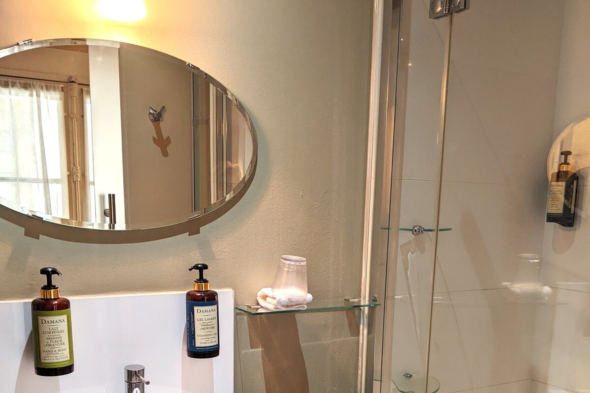 A bathroom with a white sink, a mirror, and a glass-enclosed shower.