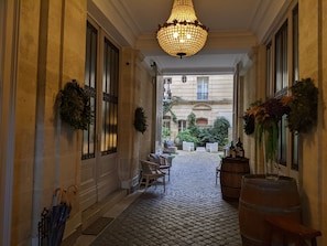 A corridor with a chandelier, potted plants, and a barrel. - L' Apparthôtel Particulier Bordeaux (Bordeaux)