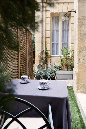 A table set with two cups and saucers, a window with curtains, and a potted plant. - L' Apparthôtel Particulier Bordeaux (Bordeaux)