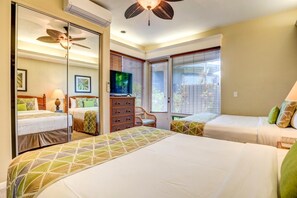 Ein Hotelzimmer mit zwei Betten, einem Fernseher, einem Deckenventilator und einem Fenster mit Jalousien.