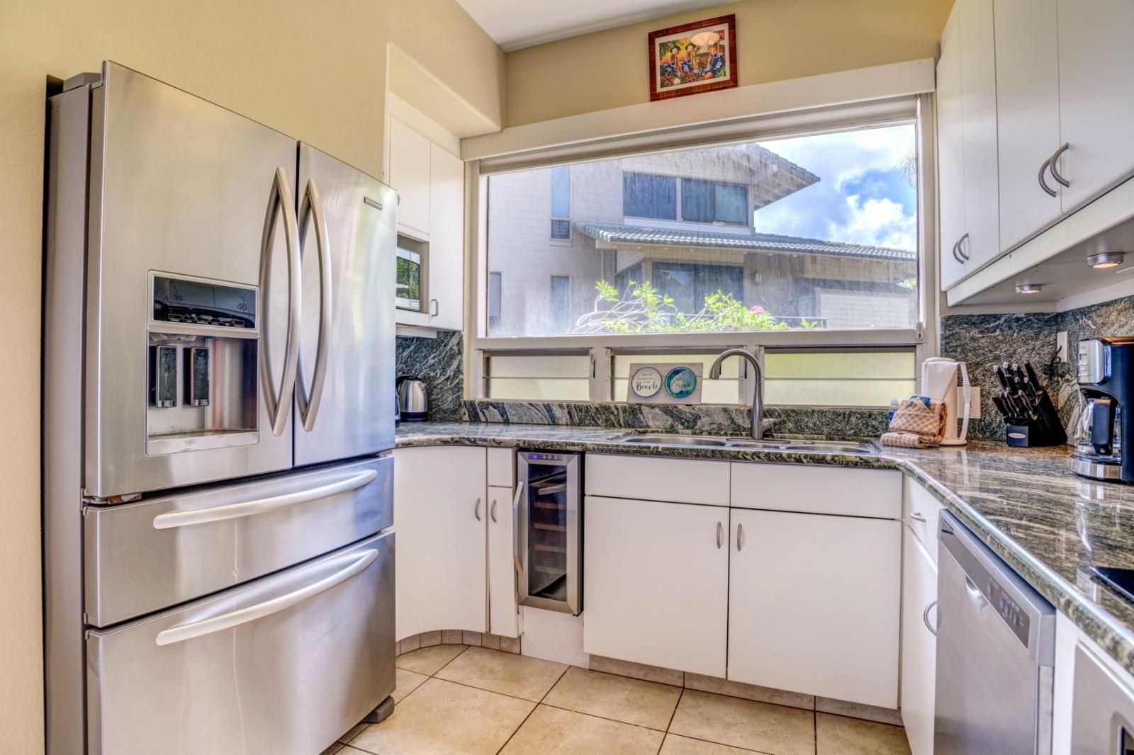 A modern kitchen with stainless steel appliances, a window with a view of buildings, and a granite countertop.
