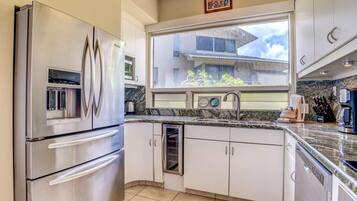 A modern kitchen with stainless steel appliances, a window with a view of buildings, and a granite countertop.