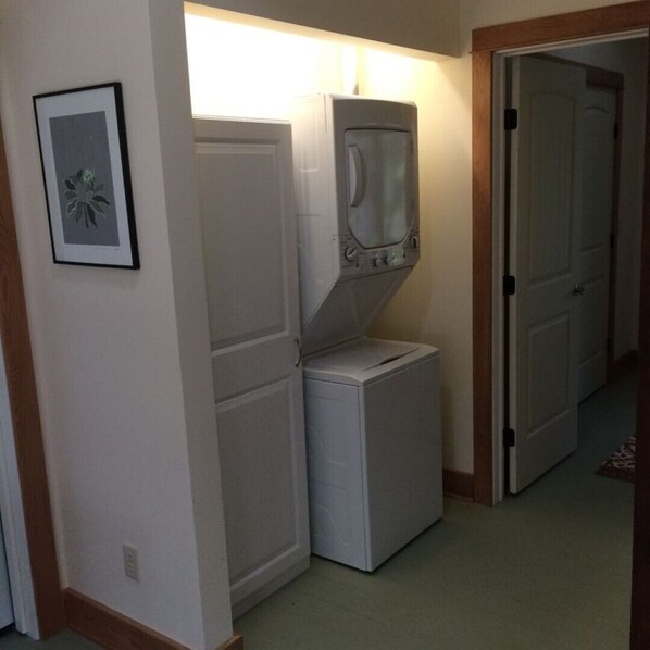 A laundry room with a washer and dryer, a framed picture on the wall, and a door leading to another room.