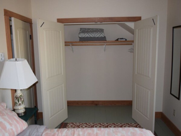 A bedroom with a bed, a bedside lamp, and a closet with a hanging shelf. - Modern Apartment; Easy Commute To Cornell University Or Ithaca College (Spencer)