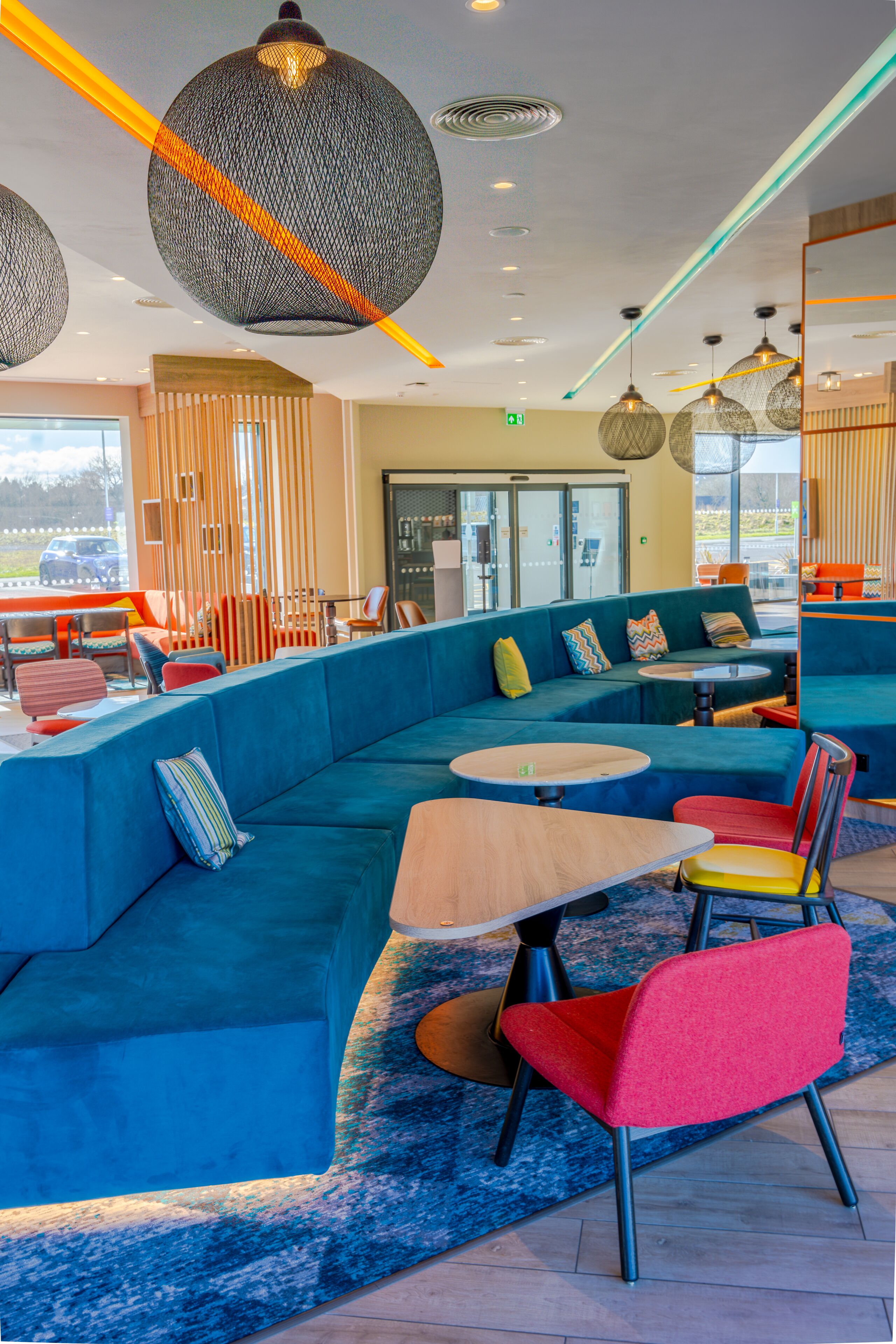 A modern lounge area with blue seating, round tables, and colorful chairs.