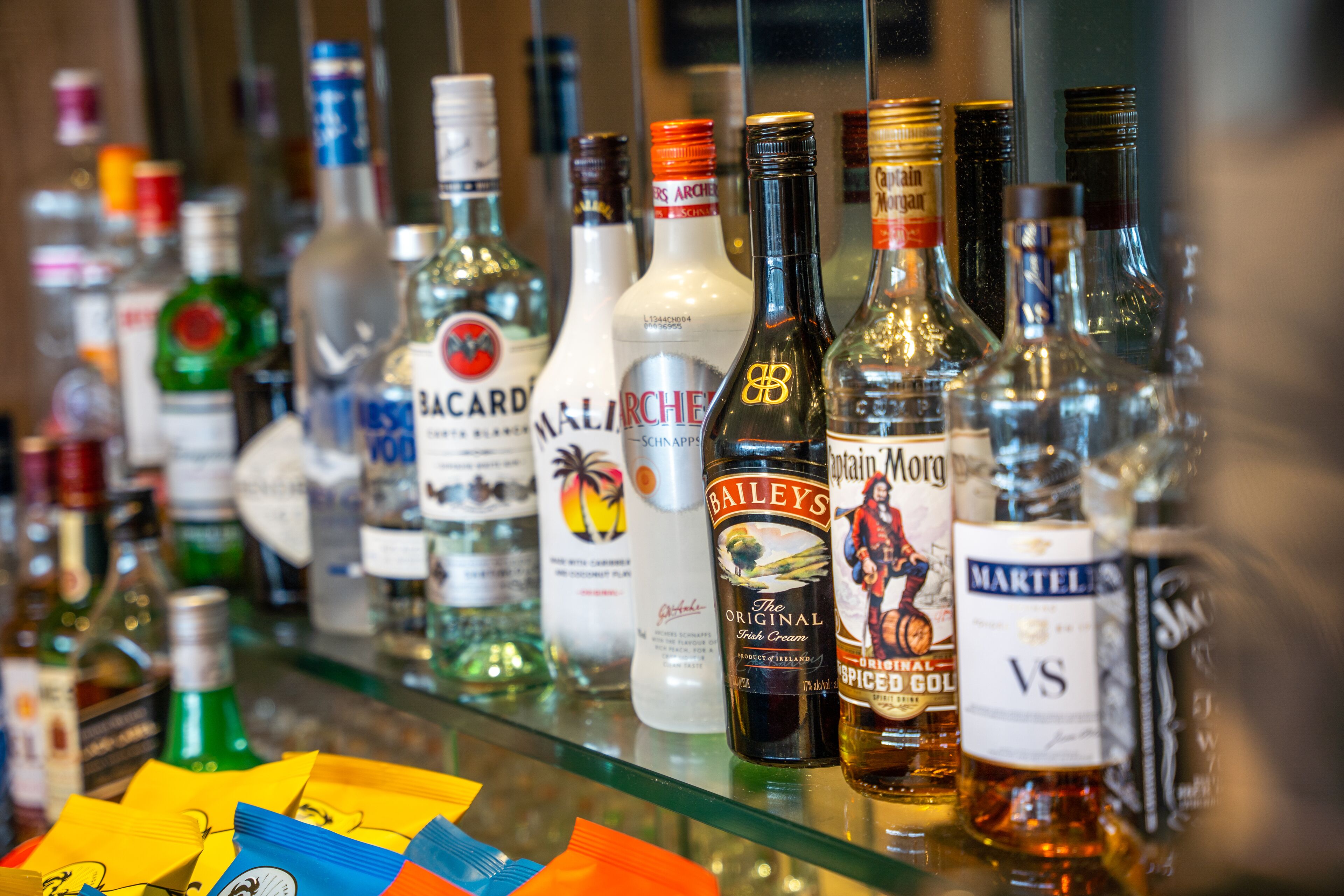 A variety of liquor bottles on a glass shelf.