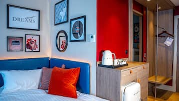 A hotel room with a bed, a dresser, and a kitchenette.