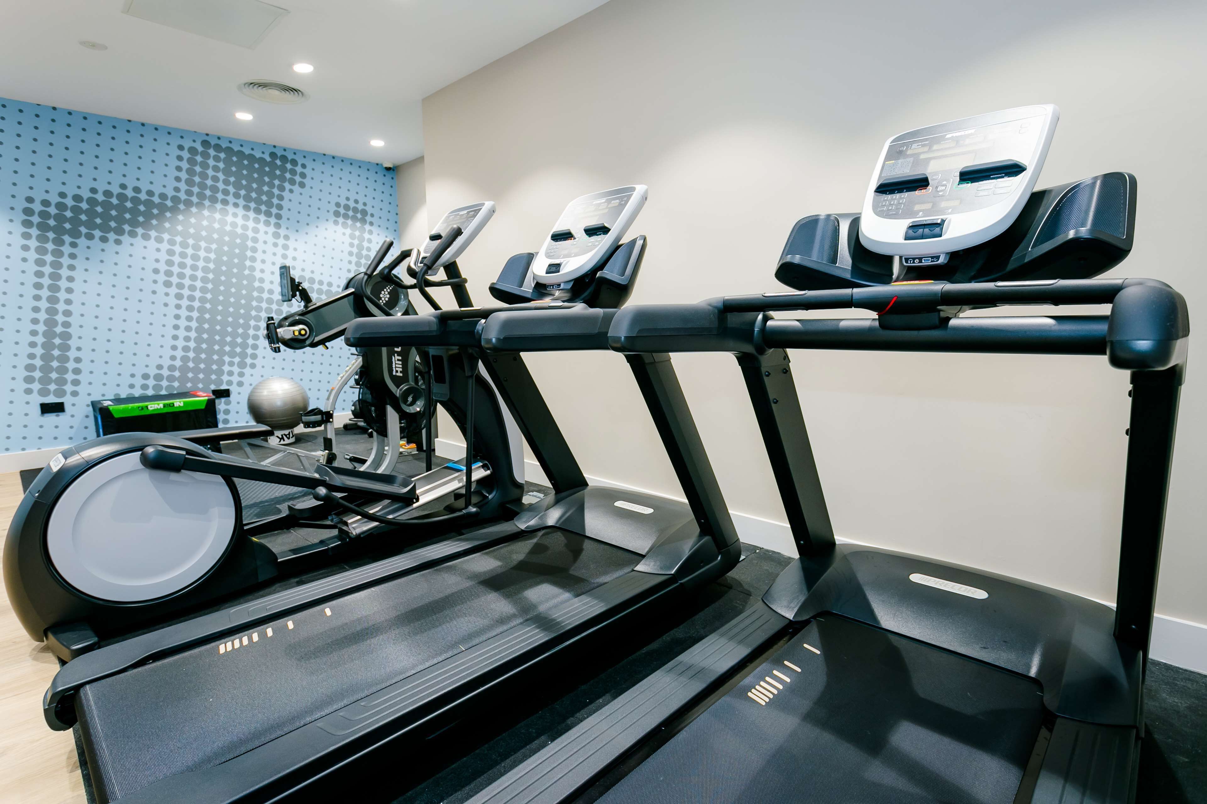 Un gimnasio con cintas de correr, una máquina de remo y una bicicleta estática.
