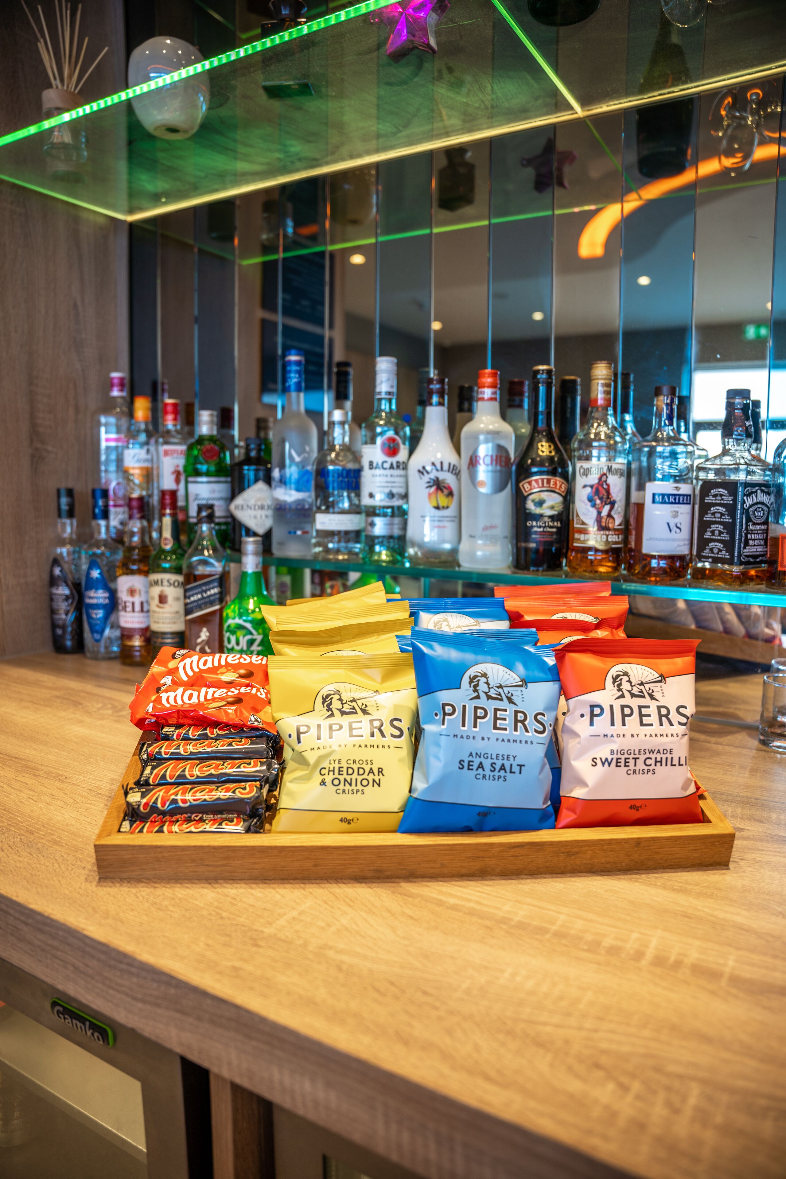 Een bar met verschillende drankflessen en lekkernijen zoals chips en snoep.