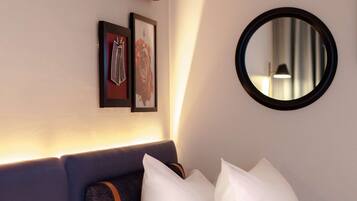Habitación de hotel ordenada con cama, sofá, espejo y cuadros en la pared.