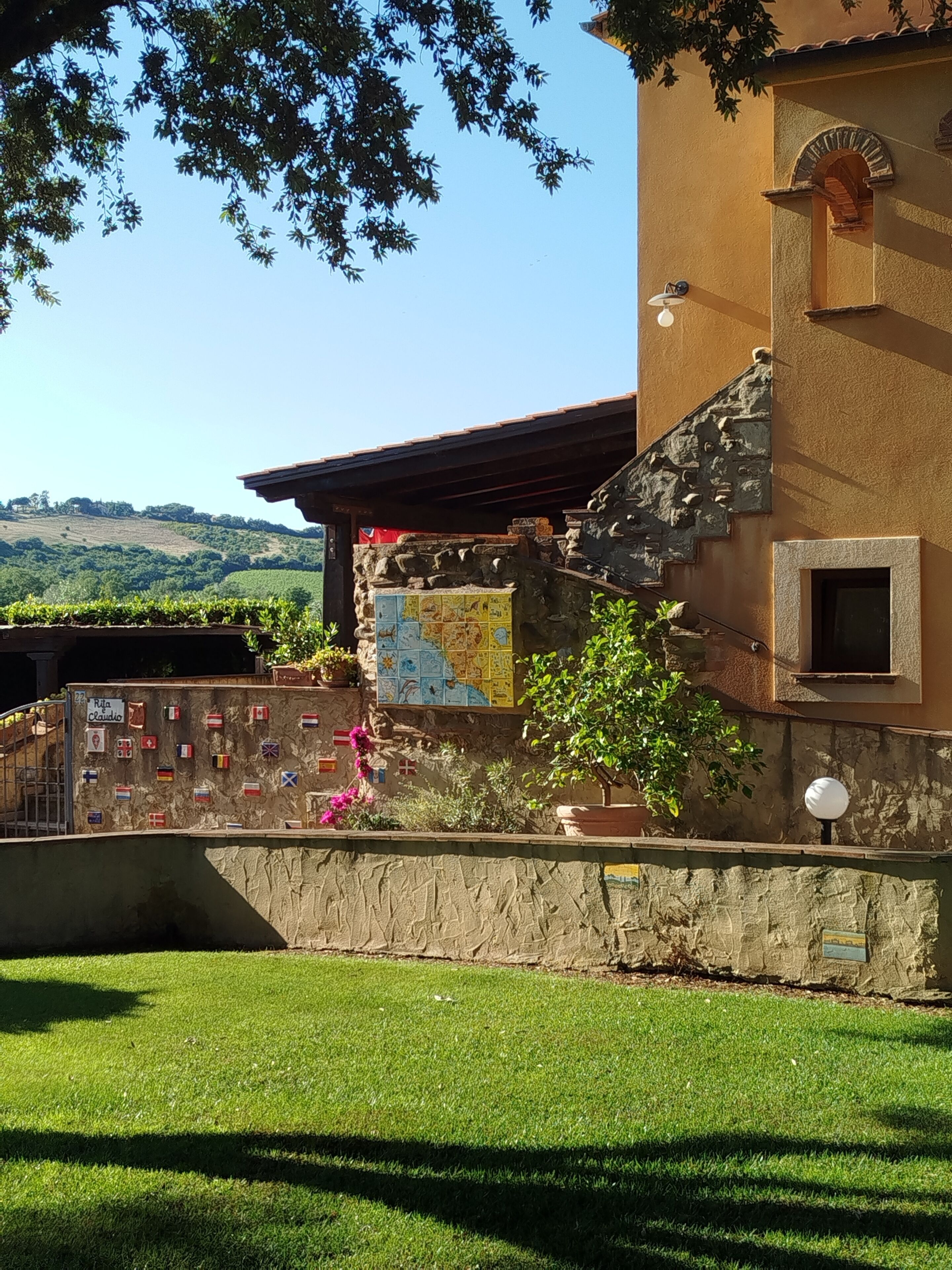 A building with a stone wall, a map, and a sign reading 'Rita & Claudio'.