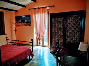 Una camera da letto con un letto, una sedia, un tavolo, una porta decorata e un quadro appeso al muro.