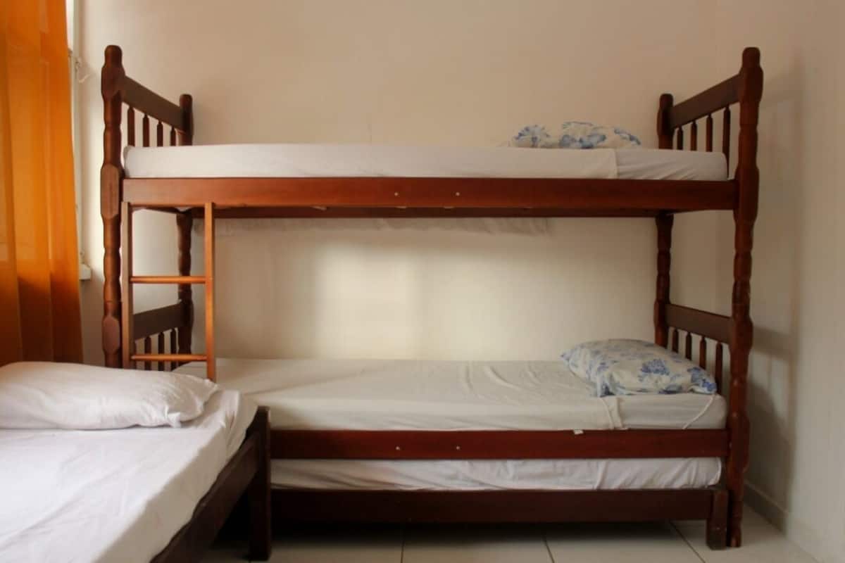 A bunk bed with a ladder, a single bed, and a small table.