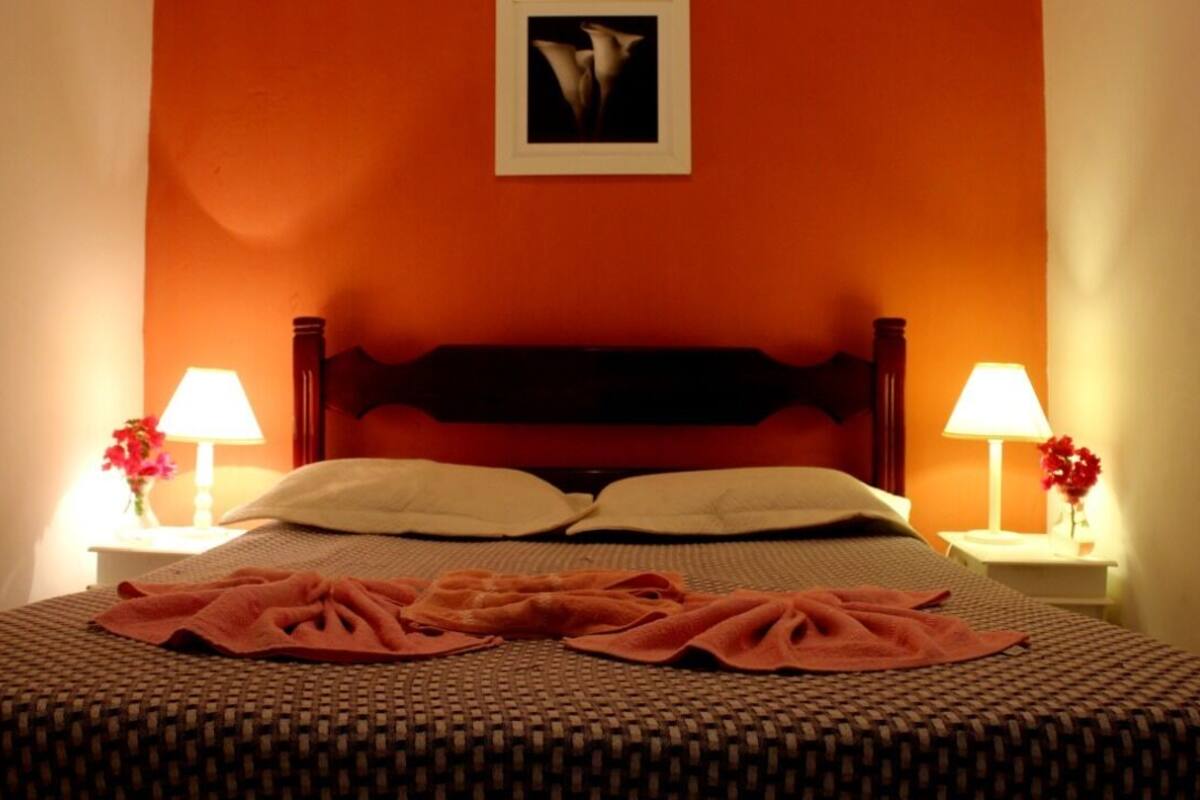 A bed with a headboard, two bedside tables with lamps, and a framed picture on the wall.