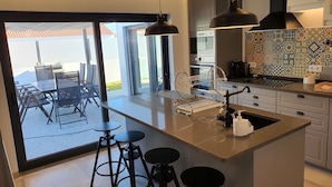 Una cucina moderna con una grande isola, sgabelli da bar e vista su un patio esterno.
