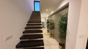 Una moderna scala dal design minimalista, che conduce a una stanza luminosa con un'ampia finestra.