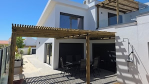 Una casa moderna con patio coperto, ampie finestre e garage.