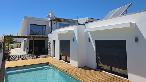 Una casa moderna con piscina, ampie finestre e garage.