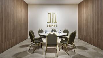 Sala de conferências com uma mesa redonda, seis cadeiras e o logotipo do Hotel Lefel.