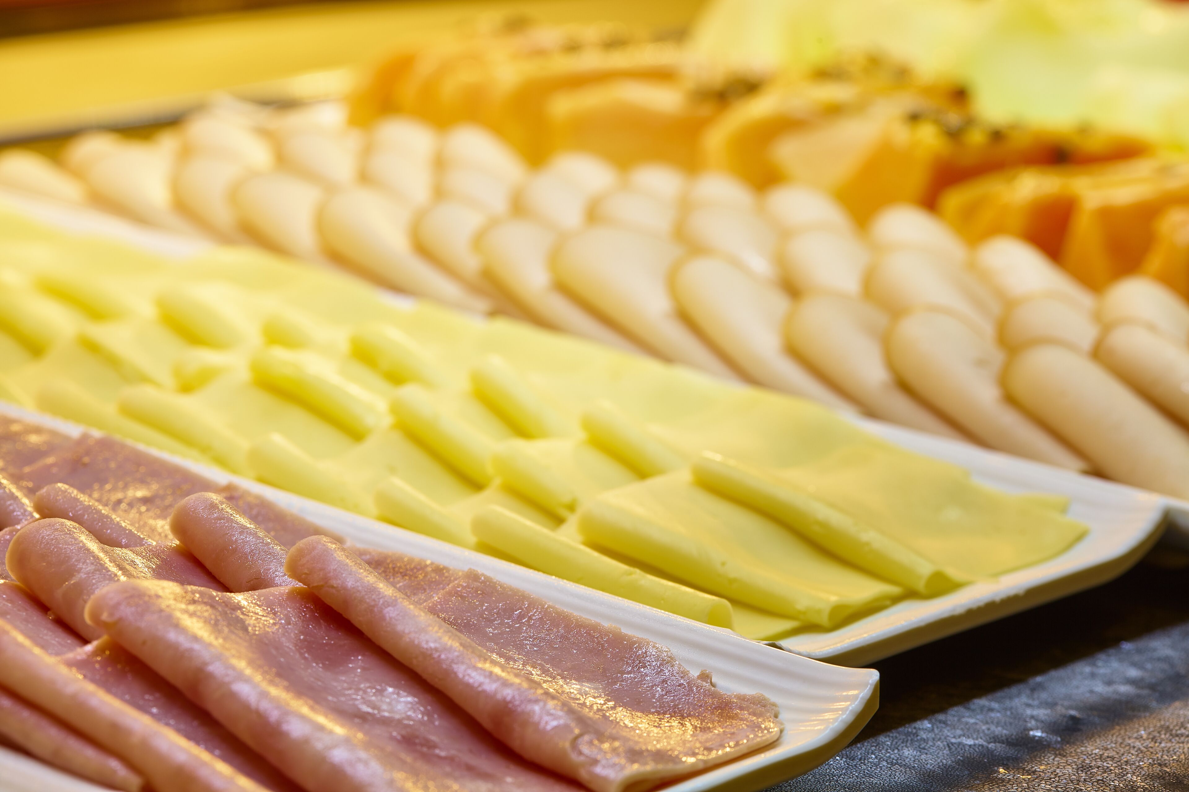 Una variedad de alimentos, entre ellos fiambres y quesos, sobre una bandeja.