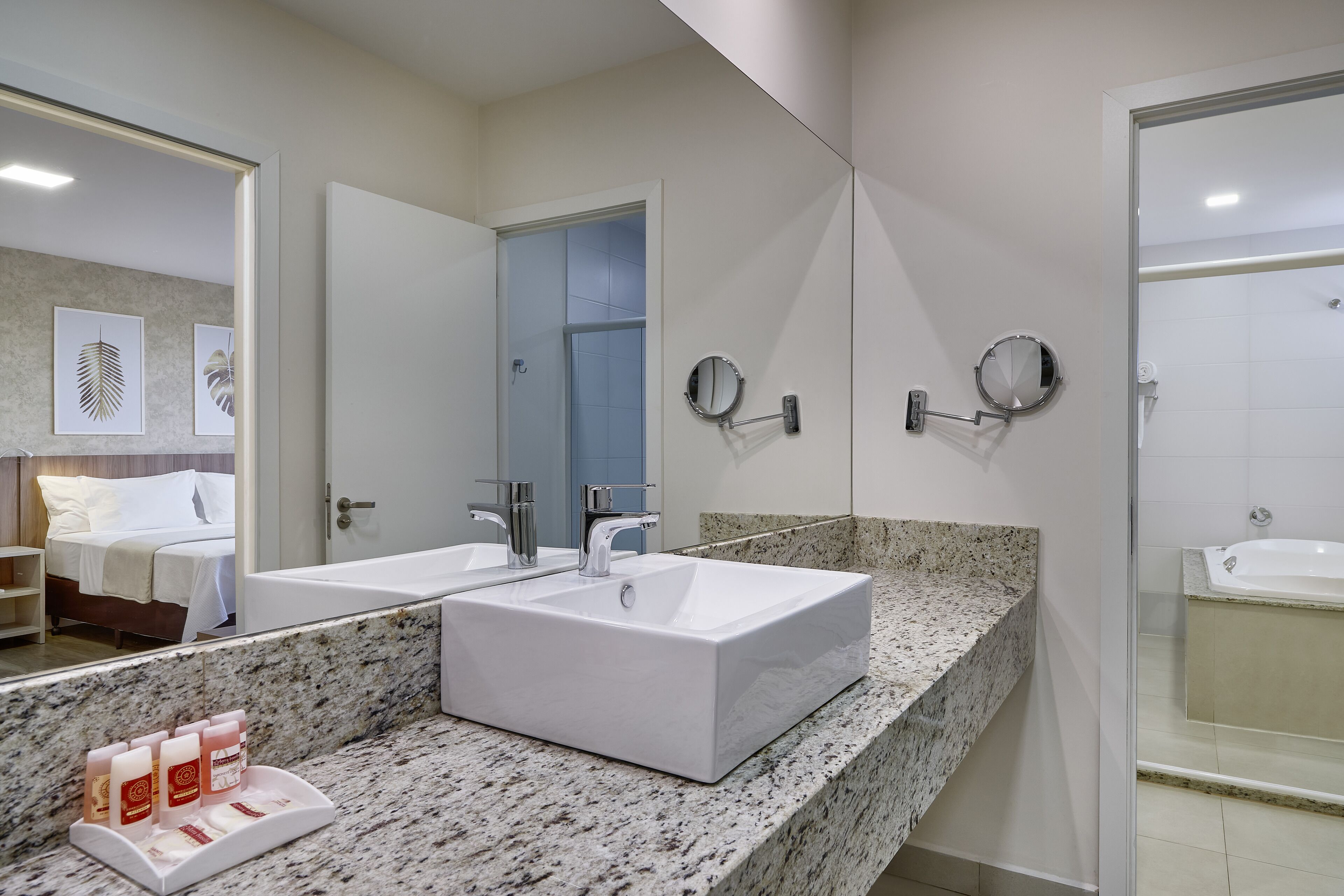 A modern bathroom with two sinks, a large mirror, and a shower area.