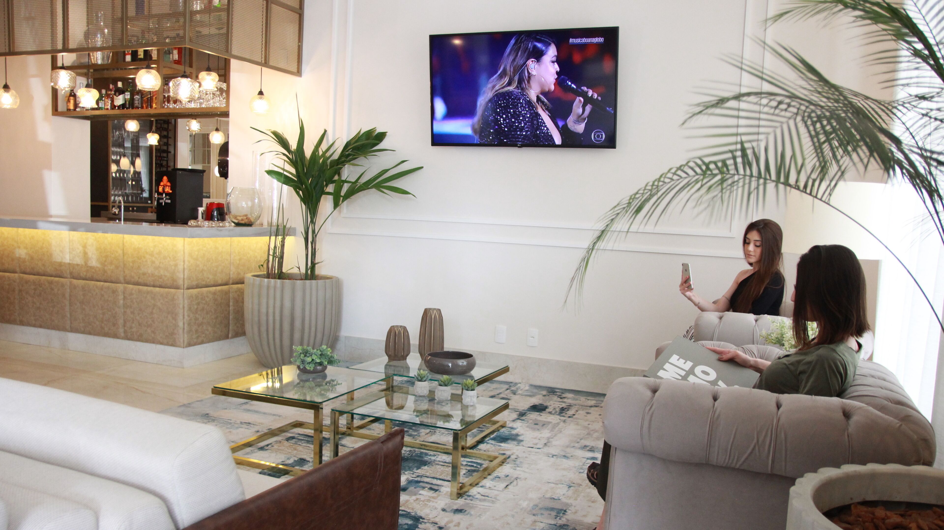 Una sala de estar moderna con una mesa de centro de vidrio, un sofá y un televisor montado en la pared.