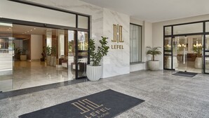 Un hall d’hôtel aux murs de marbre, avec un comptoir d’accueil et des plantes en pot.