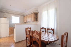 A kitchen with wooden cabinets, a window, and a dining table with chairs.
