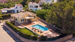Ein modernes, zweistöckiges Haus mit Swimmingpool, überdachter Terrasse und gepflegtem Garten.