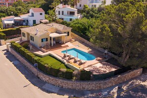 Une maison moderne à deux étages, dotée d’une piscine, d’un patio couvert et d’un jardin bien entretenu.