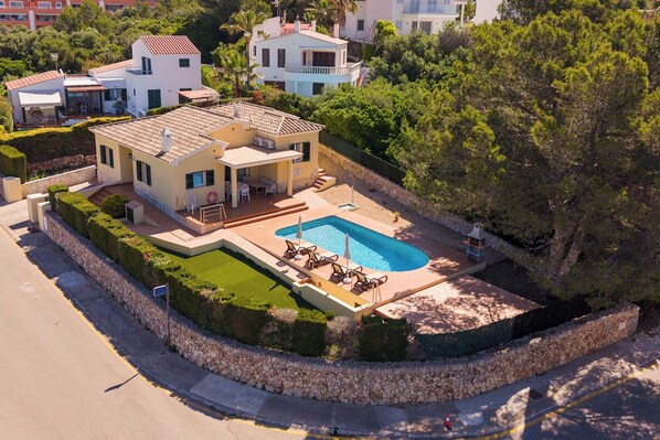 A modern two-story house with a swimming pool, a covered patio, and a well-maintained garden.
