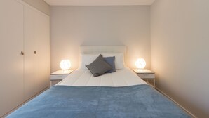 A bedroom with a large bed, two bedside tables with lamps, a wardrobe, and a headboard. - Bright & Sunny Beach House (Leça da Palmeira)