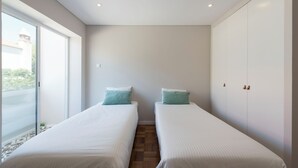 A bedroom with two beds, a sliding glass door to a balcony, and a wardrobe with a mirror. - Bright & Sunny Beach House (Leça da Palmeira)