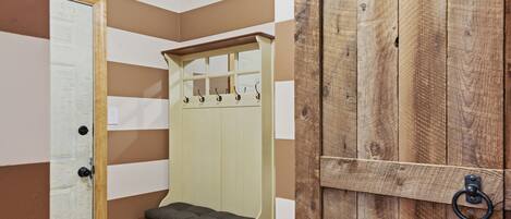 Una habitación con un banco de madera, un perchero y una puerta.