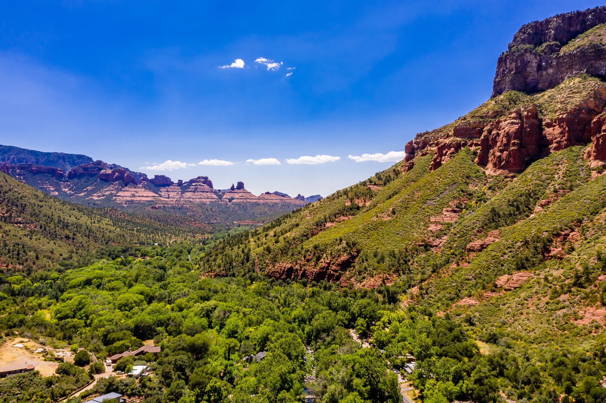 A mountainous landscape with dense green vegetation and a clear blue sky.