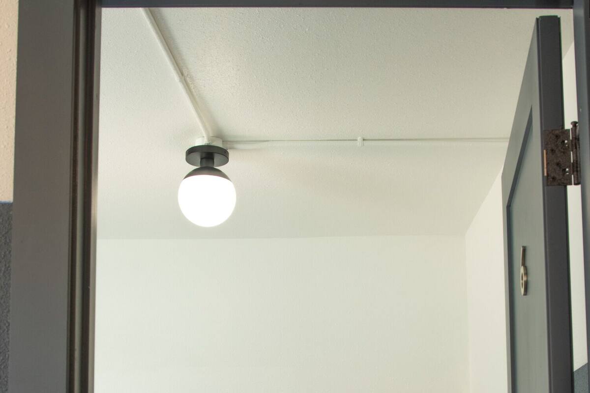 A room with a bed, a white pillow, and a ceiling light.
