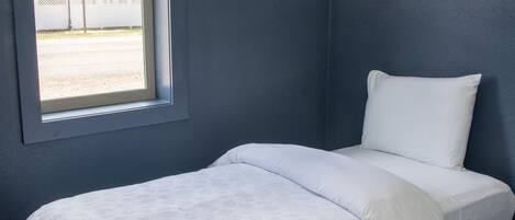 Un dormitorio con una cama individual, una ventana y una pared azul oscuro.
