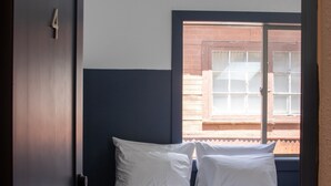 A bedroom with a bed, a window, and a door.