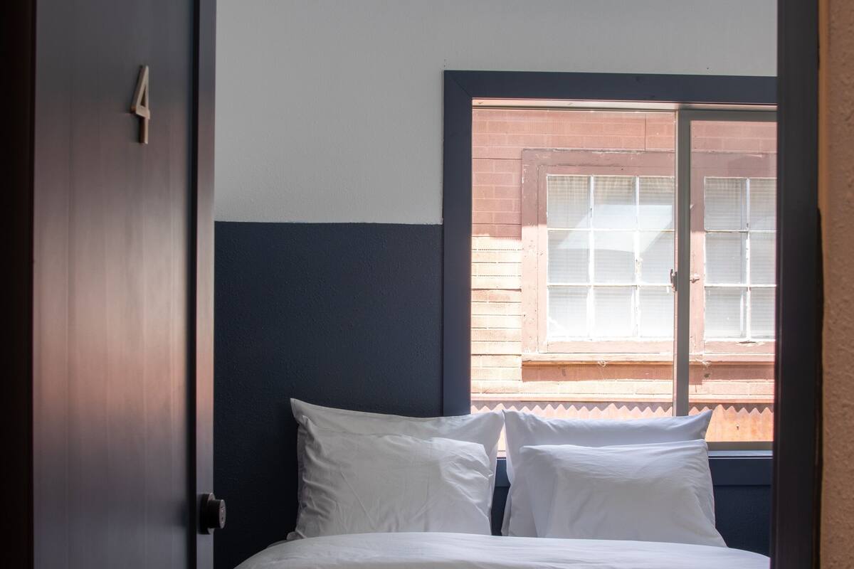 A bedroom with a bed, a window, and a door.