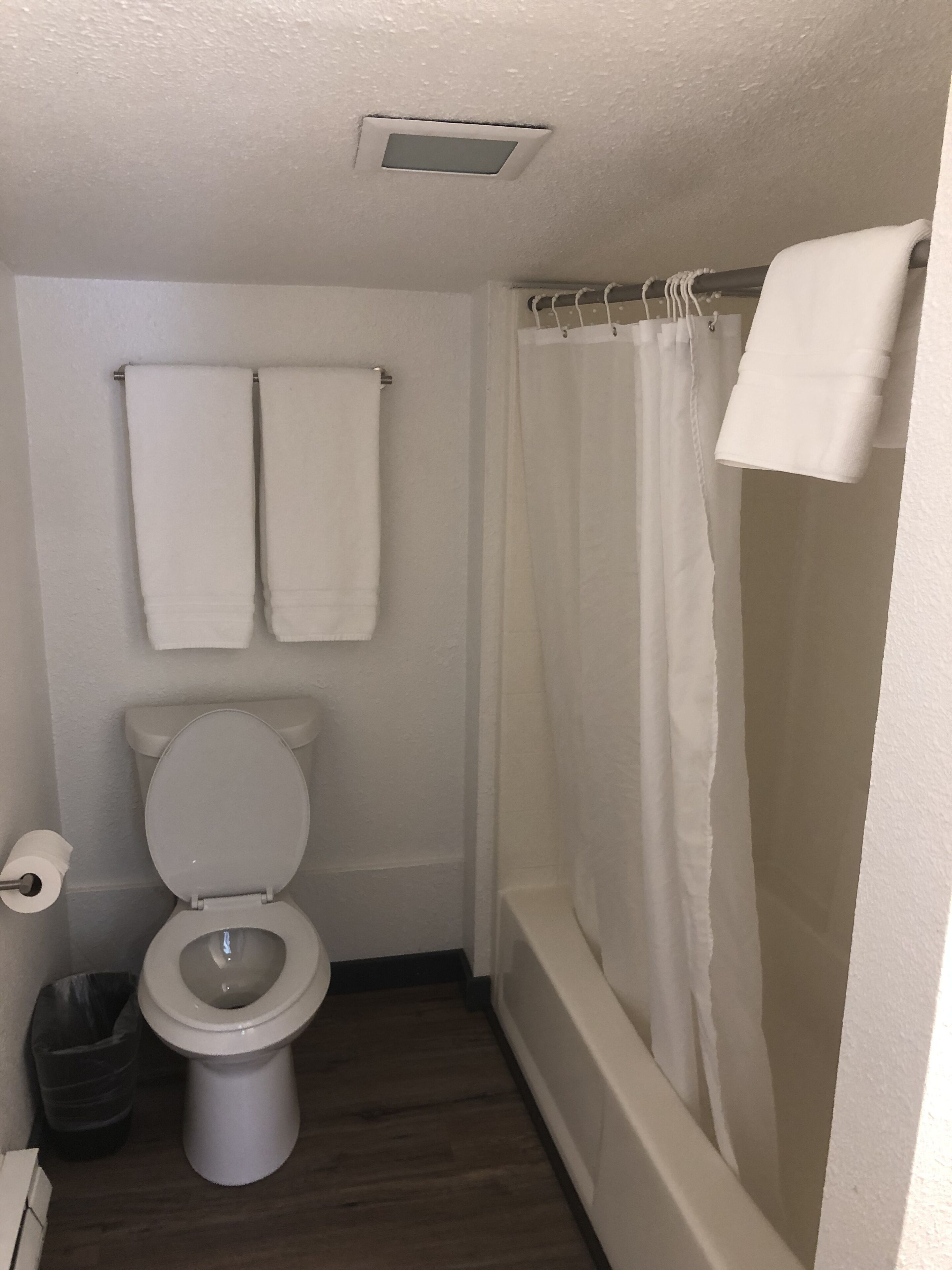 A small, clean bathroom with a toilet, a shower curtain, and two towels hanging on the wall.