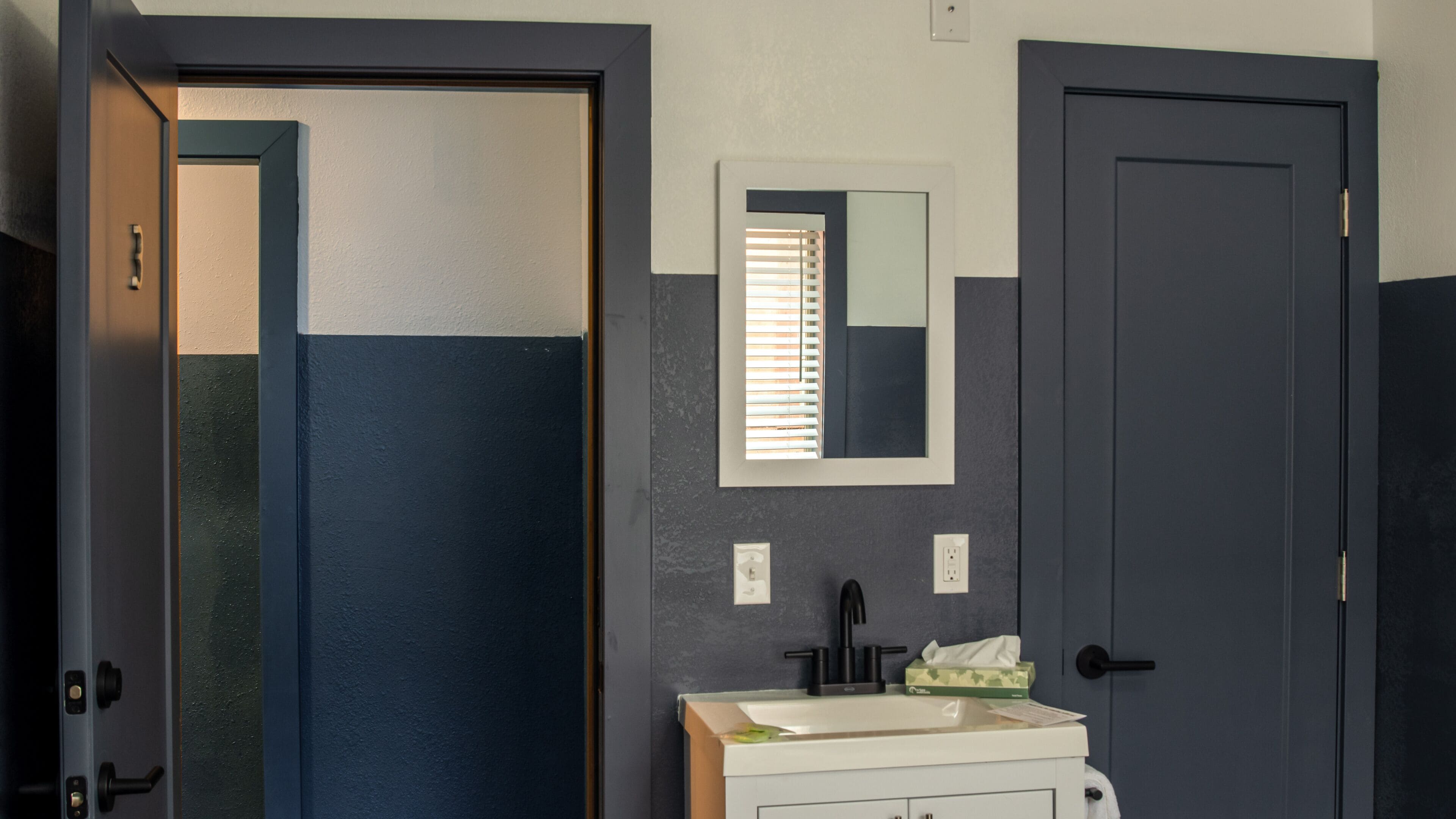 A bathroom with a white sink, a mirror, and a door.