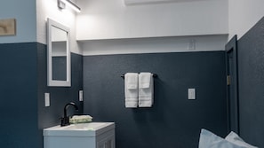 A bathroom with a dark blue wall, a white sink, a black faucet, a mirror, and a towel rack with two white towels. - Kendall Mountain Lodge (Silverton)