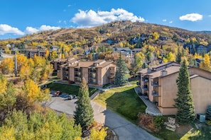 A residential area with multi-story buildings, a parking lot, and a hilly backdrop.
