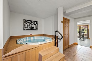 A hot tub in a corner with wooden steps and a door leading to an outdoor area. - Ski-In/Out Retreat | Sauna, Hot Tubs & Shuttle (Steamboat Springs)