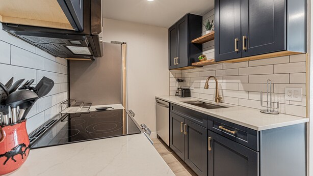 A modern kitchen with dark cabinets, a white countertop, and a stainless steel range hood. - Stylish Ski-In/Ski-Out Condo with Sunset Views and Slope Access/Sleeps 5! (Steamboat Springs)