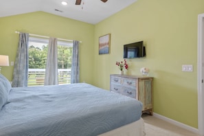 A bedroom with a bed, a dresser, a television, and a window with curtains. - The E Gull Has Landed: Private Spa, Shared Pool (Kill Devil Hills)