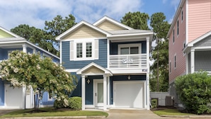 A two-story residential building with a garage, a balcony, and a small porch. - The E Gull Has Landed: Private Spa, Shared Pool (Kill Devil Hills)