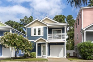 Stunning two-story home with a charming front porch and garage, set amidst lush trees and beautifully maintained gardens.