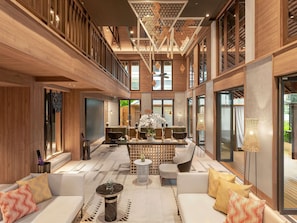 Un interior espacioso y moderno con techo alto, paneles de madera y una zona de estar central con sofás y una mesa de centro.