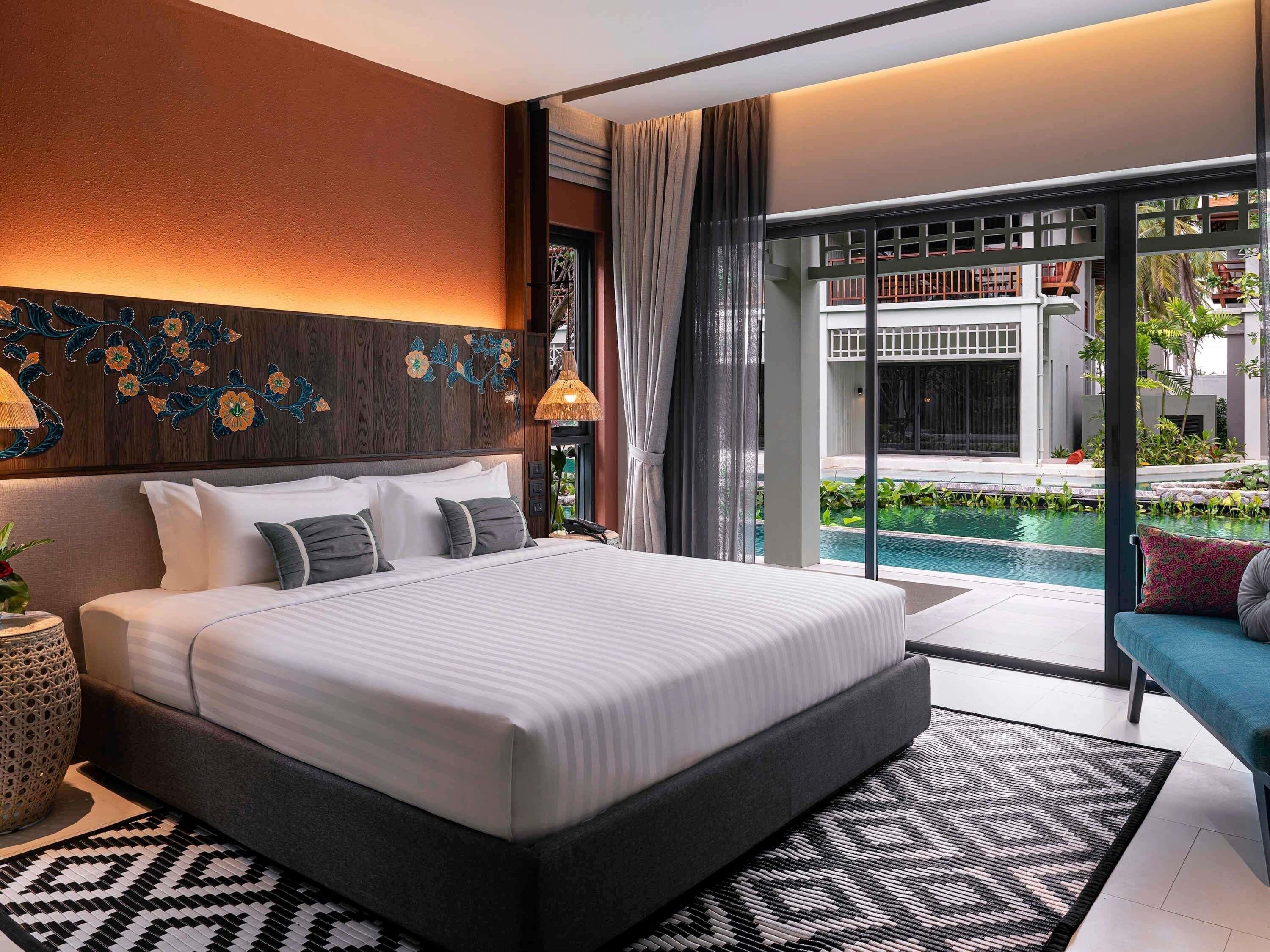A modern bedroom with a large bed, a view of a swimming pool, and a balcony.